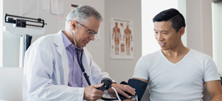 doctor taking man's blood pressure in doctor's office