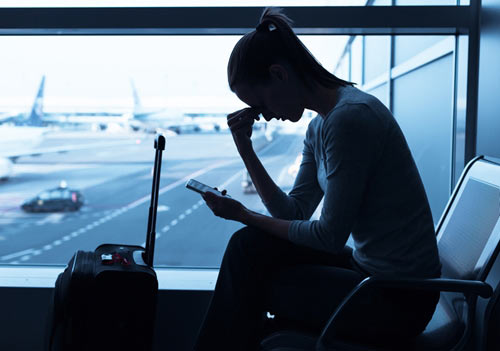 woman resting head on hand in airport waiting for flight